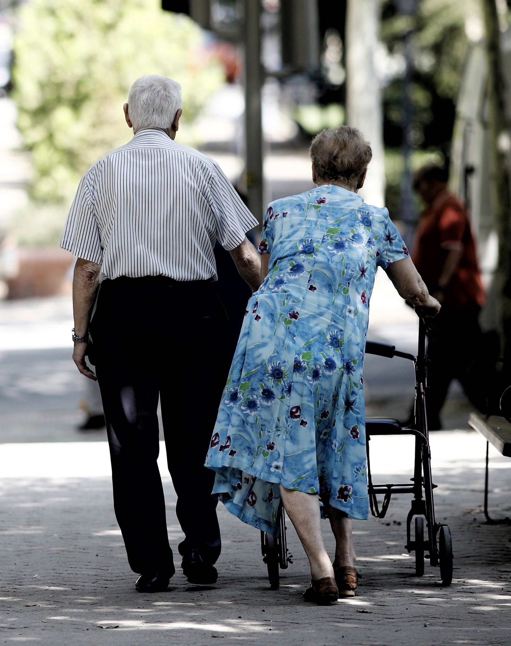 Archivo - Una pareja de pensionistas pasea con un andador por un parque de Madrid.